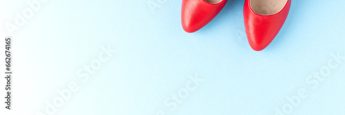 Red high heels on blue background with copyspace. Women’s shoes