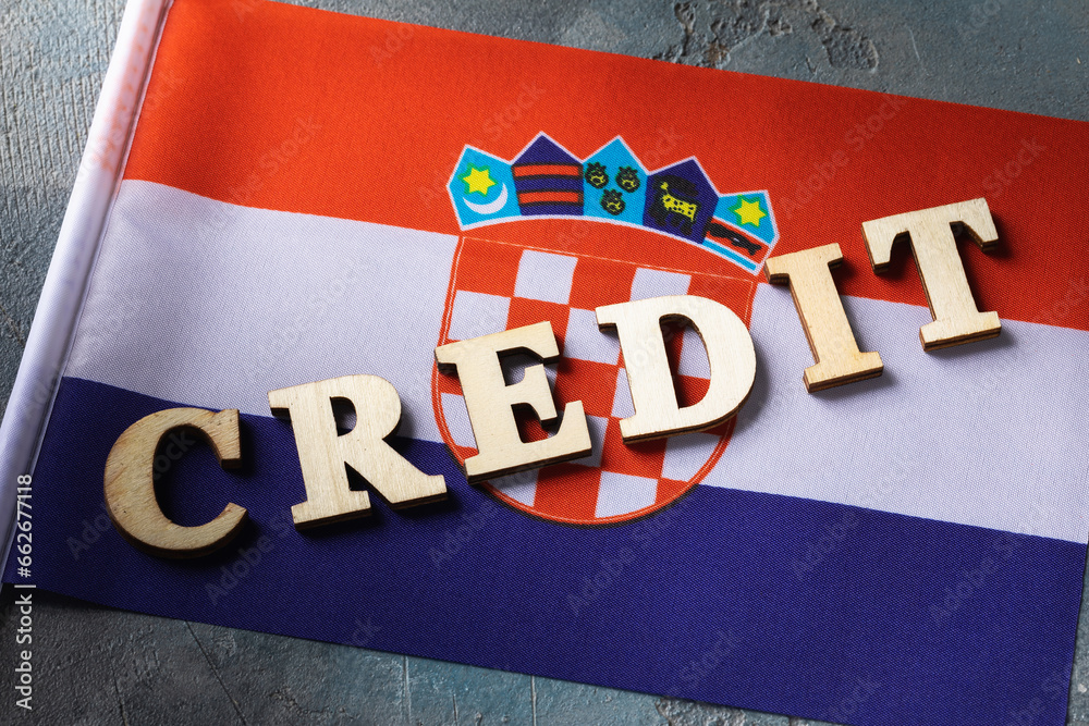 Text from wooden letters and flag on abstract background, concept on the theme of the debt burden of the people of Croatia