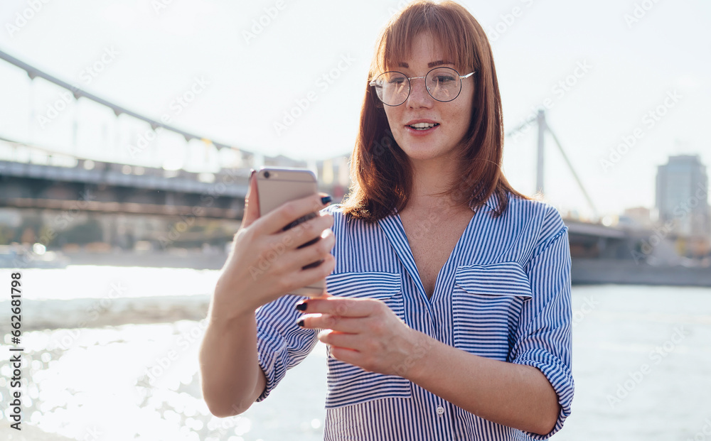 young caucasian girl making photo on mobile phone for blogging in social media on urban settings