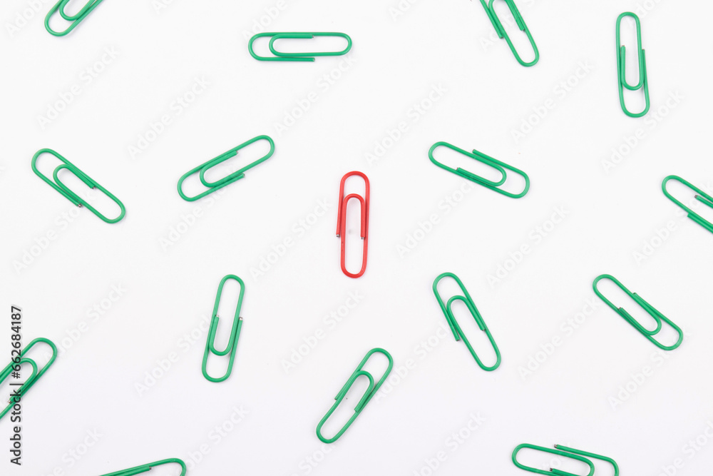 Red paperclip with multiple green paperclip on white background, unique concept