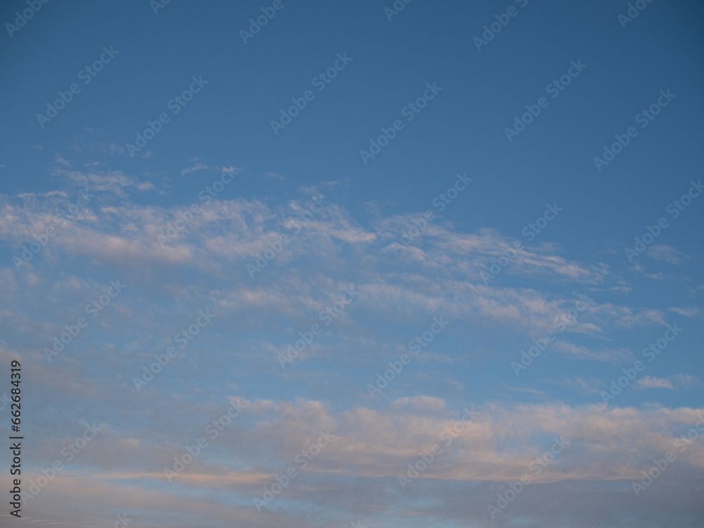 Blue sky after rain,. Beautiful Cumulus clouds flying across the sky, sunset rays, pink shades in the clouds, deep blue sky