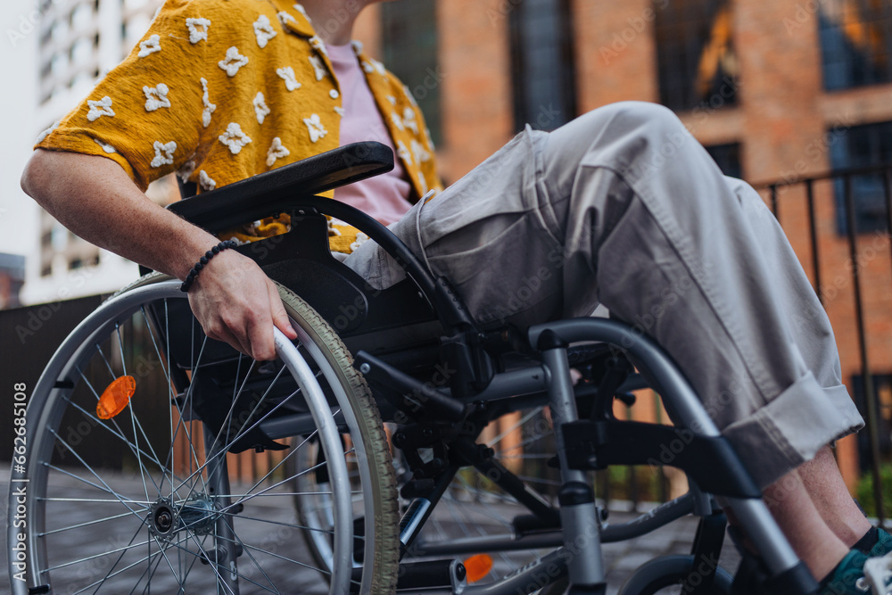 Obraz premium Close up of young Gen Z boy in a wheelchair in the city. Inclusion, equality, and diversity among Generation Z.