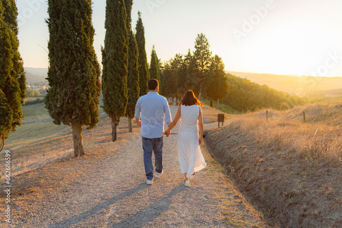 coppia ragazzo e ragazza felici si tengono per la mano su viale al tramonto