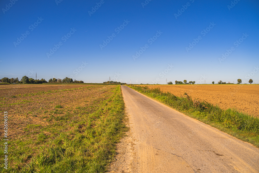 Ein gerader und einsamer Weg durch das flache Land mit Feldern.