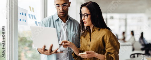 Business people standing in an office and using a laptop