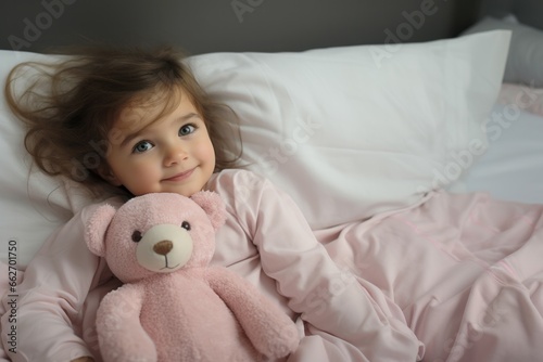 Happy little girl sleeps with toy bear on the bed at home. Top down view