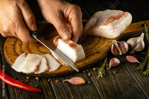 Cutting lard into small pieces before preparing sandwiches for snacks. National Ukrainian food. Peasant products. Male hands with a knife