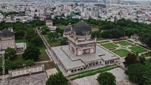 areal drone shot of Mohammad Quli Qutub Shah tomb at Qutub Shahi Tombs, hyderabad, telangana with crowded buildings at the background photo