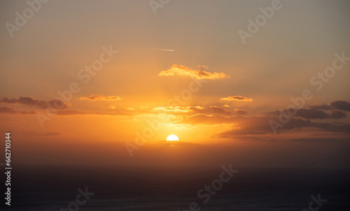 Sunset through and behind the cloud over the sea background. Sunbeam colors golden the sky