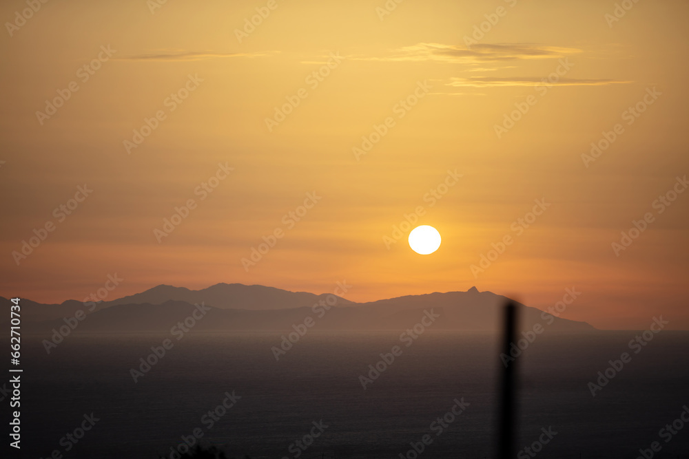Sunset behind mountain silhouette over the sea on colorful sky background. Space