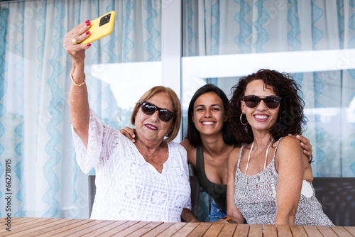 Foto Three happy women of different ages taking a selfie with the smartphone and look
