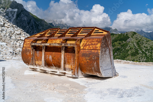 Industrial shot illustrating the production of marble. Construction excavator not visible but with bagger bucket on site of white Carrara marble in the quarry. Landscape view of industrial tools.