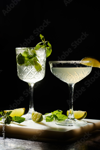two esthetic cocktails decorated with mint and lime slices on black backdrop, concept