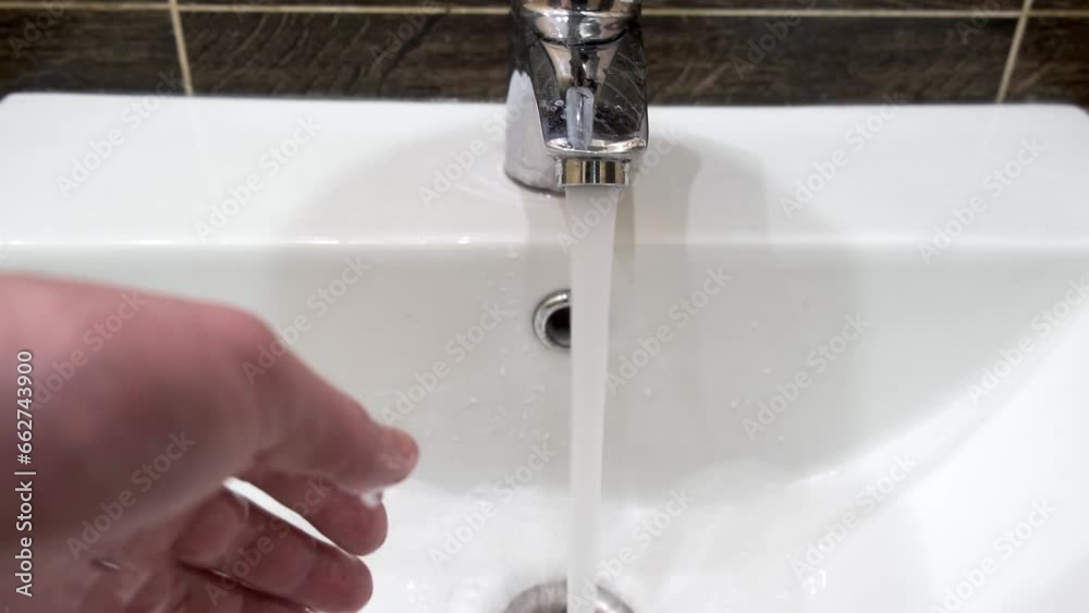 Hands are rinsed under running water over a sink, close-up, first-person view. Hands are rinsed under running water over a sink, close-up, first-person view.