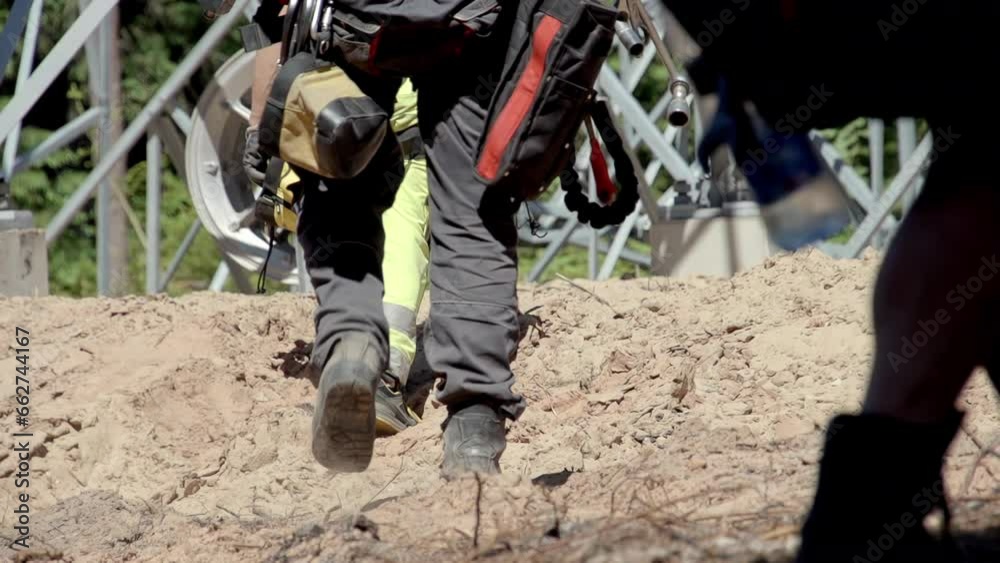 Low angle close up shot of electricians in protective gear as they walk through drying earth to repair a power pole. Dangerous work of electricians Low angle close up shot of electricians in protective gear as they walk through drying earth to repair a power pole. Dangerous work of electricians