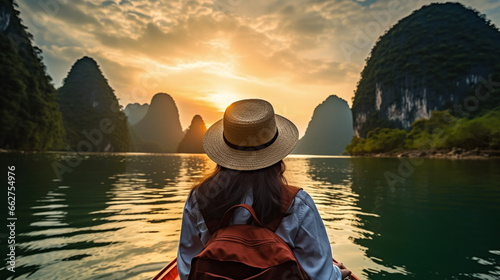 Woman in Hat Enjoying Sunset on Boat Surrounded by Mountains © Kiss