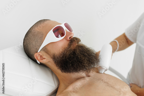 Brutal man having laser hair removal procedure in cosmetic center. Removes pigmentation in cosmetic clinic. Intensive Pulsed Light Therapy. Anti-aging treatments. photo