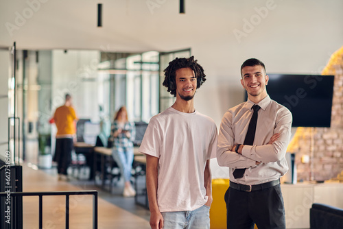 A group of colleagues, including an African American businessman and a young leader in a shirt and tie, pose together in a modern coworking center office, representing a dynamic blend of