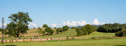 hay bales in green rolling countryside of french jura in summer under blue sky