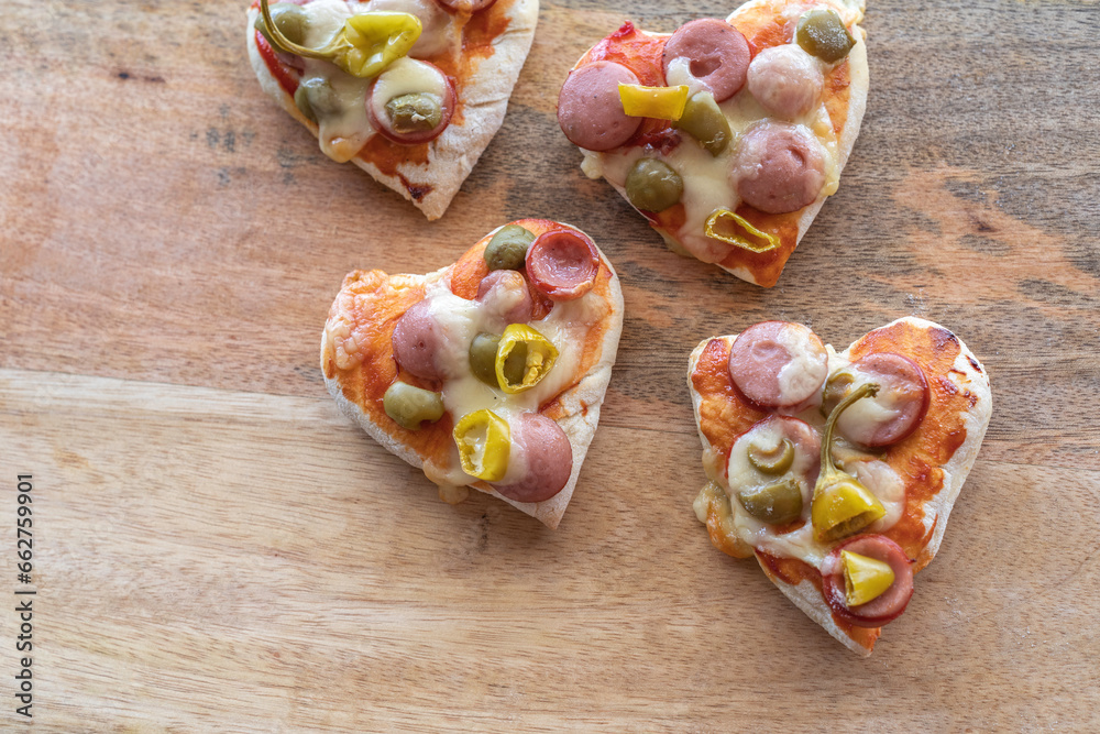 Heart shaped mini pizzas for Valentine's Day on wooden background.