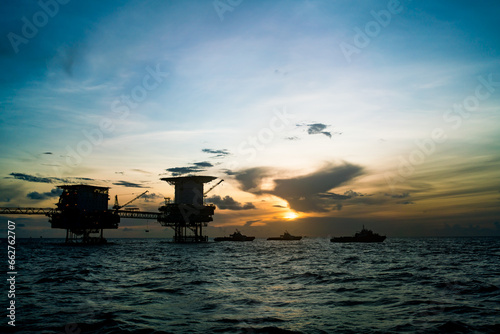 Offshore oil and gas drilling rig during the crew ferrying crew to the rig during sunset showing dark silhouette
