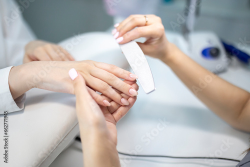 manicurist doing nail polish using file in manicure salon