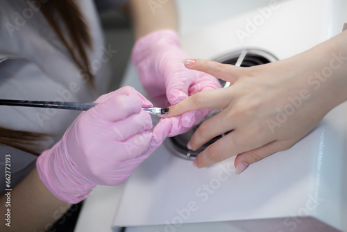 manicurist paints nails with gel polish, close up