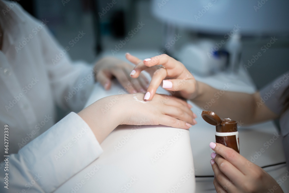 manicure master holding a client's hand and applying cream