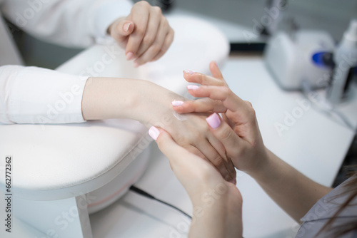 manicure master holding a client s hand and applying cream