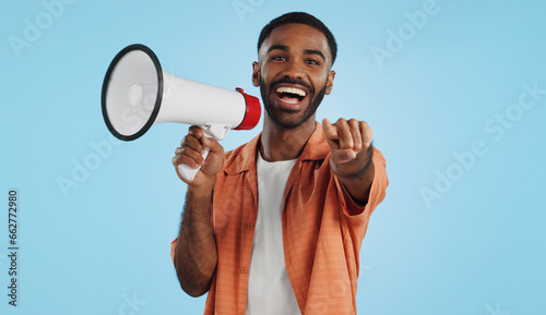 Young man, megaphone and announcement, choice or broadcast for winner, join us or winning opportunity in studio. Face of african person with voice, pointing you and competition on a blue background