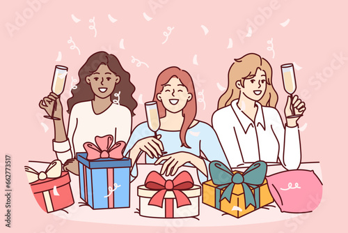 Women celebrate bachelorette party and wish girlfriend happy birthday, drinking champagne and presenting boxes with gifts. Diverse girlfriends posing with smile during fun bachelorette party