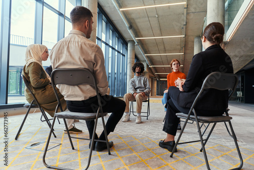 A diverse group of young business entrepreneurs gathered in a circle for a meeting, discussing corporate challenges and innovative solutions within the modern confines of a large corporation