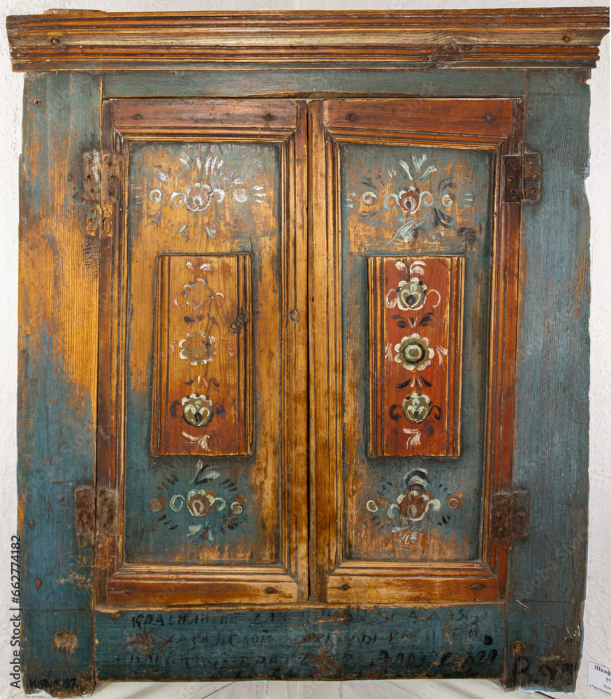 The doors of an old wooden cabinet with drawings and peeling old paint The doors of an old wooden cabinet with drawings and peeling old paint