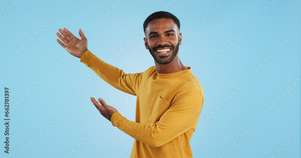 Happy, face and man with hand pointing in studio for news, presentation or platform offer on blue background. Smile, portrait and male model show promo, launch or space for coming soon announcement Happy, face and man with hand pointing in studio for news, presentation or platform offer on blue background. Smile, portrait and male model show promo, launch or space for coming soon announcement