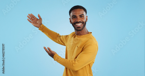 Happy, face and man with hand pointing in studio for news, presentation or platform offer on blue background. Smile, portrait and male model show promo, launch or space for coming soon announcement