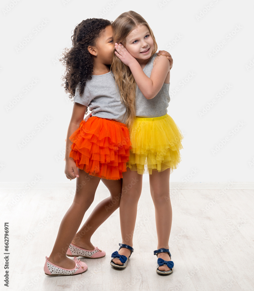 two little pretty girls in colorful skirts talking and laughing isolated on white background two little pretty girls in colorful skirts talking and laughing isolated on white background