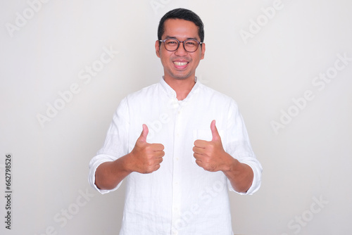 Adult Asian man smiling happy and give two thumbs up photo