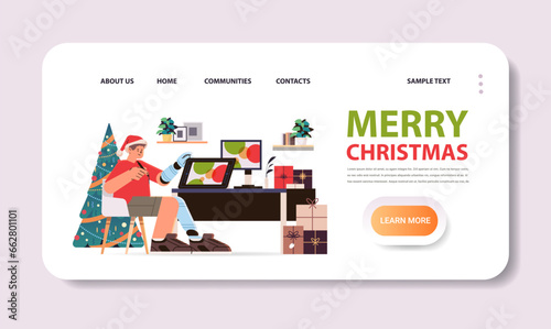 disabled man in santa claus hat graphic designer with replaced robotic leg and arm guy working on laptop people with disabilities