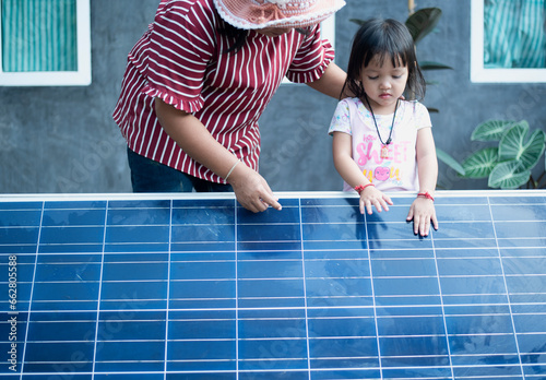 A happy Asian family admires the solar panels they just installed at their home.