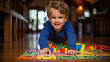 3 year old boy playing on the floor with colored plastic construction pieces. His environment is in a modern house, image with warm and pleasant tones.