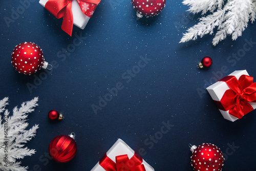 Merry Christmas and Happy Holidays greeting card, frame, banner. New Year. Noel. Red and white Christmas red ornaments and gifts on blue background top view. Winter xmas holiday theme.