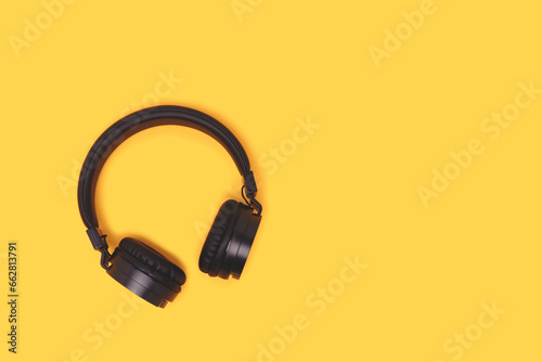 Black wireless headphones on a yellow background. Place for text.