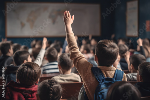 Elementary school student raising his hand to ask the teacher something during class at classroom.