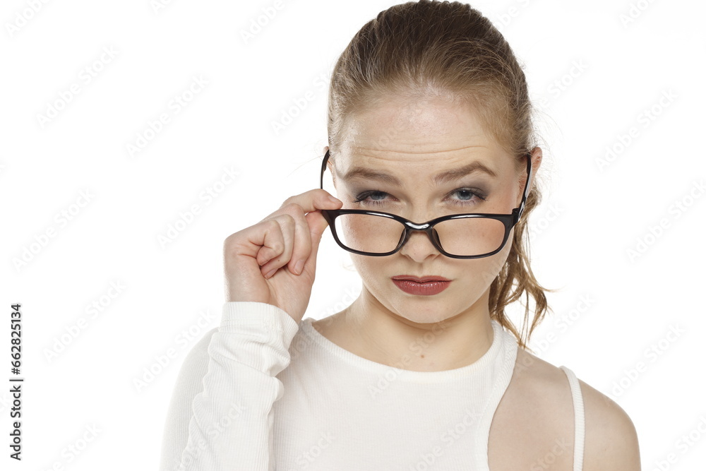 Portrait of young blonde woman with glasses looks in disbelief on a white background Portrait of young blonde woman with glasses looks in disbelief on a white background
