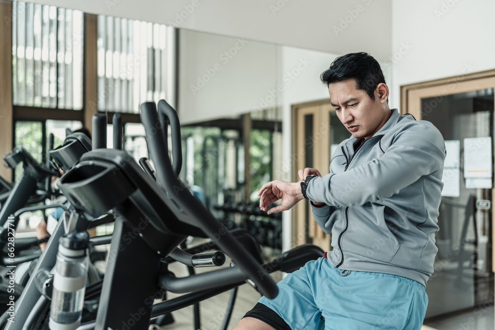 A man checking at smartwatch during training  at gym. Fitness, workout and traning at concept.