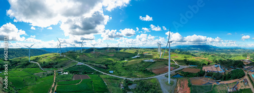 Panoramic view of Powerful wind turbine farm for pure energy production on beautiful clear blue sky with white clouds and wind farm background. Wind turbines for the generation of electricity