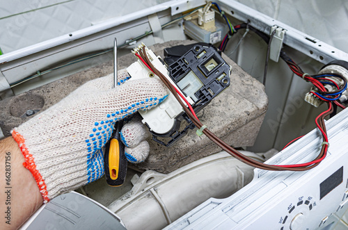 Service engineer repairs the door lock in a washing machine.