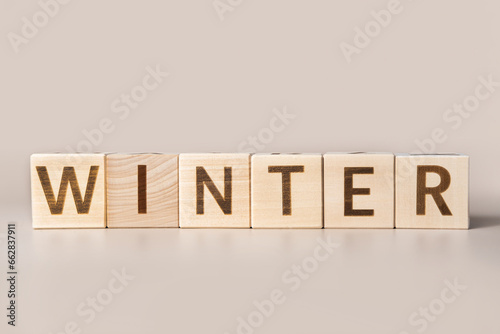 The Word Winter on wooden cubes on a beige neutral studio background. Copy Space. Written. Text words matter. Christmas decorations. Inscription Happy New Year business concept strategy. New Start Up