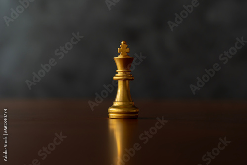 Close up the golden queen chess piece standing alone on a chessboard on dark background.