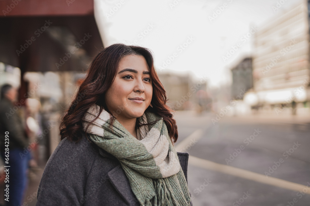 Young multiracial woman waiting at bus station in the city - Asian girl outdoor during winter time